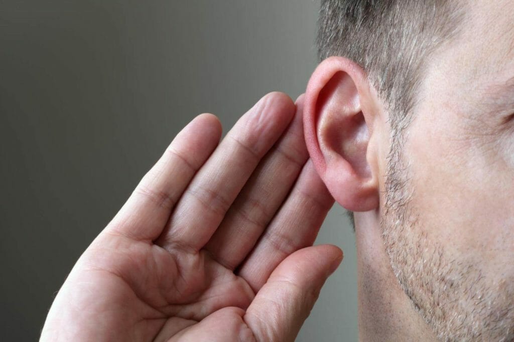 Man placing his hand to his ear