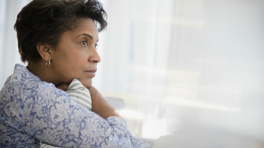 Pensive older Black woman clutching pillow