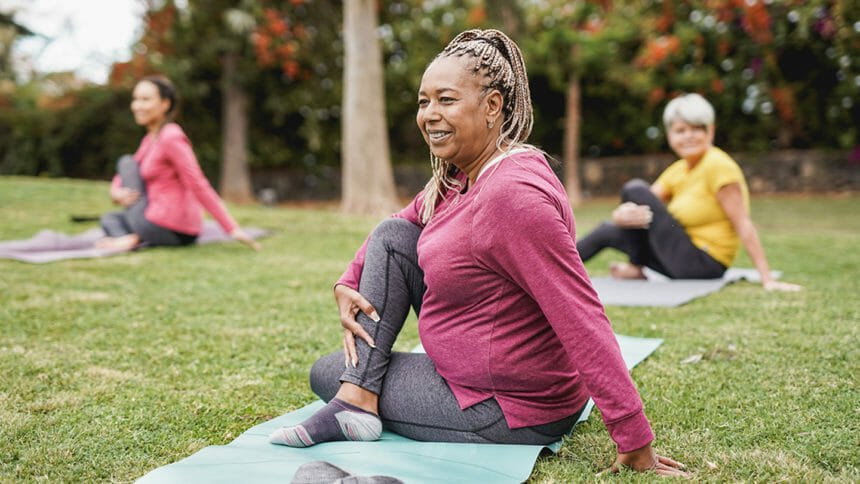 Multiracial women doing yoga exercise with social distance for coronavirus outbreak at park outdoor - Healthy lifestyle and sport concept