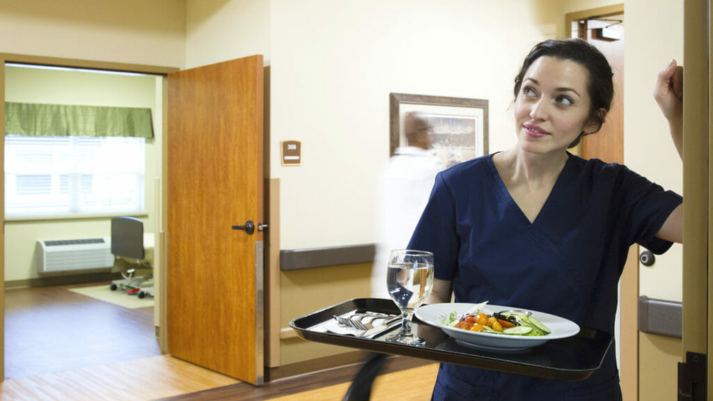 Nurse carrying tray of food in hospital