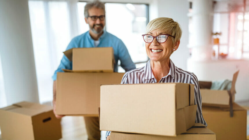 older man and woman holding moving boxes