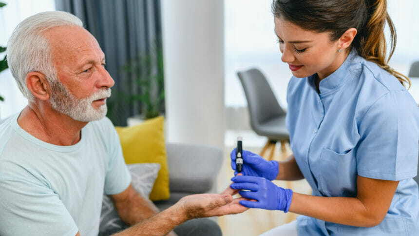 A nurse uses a glaucometer to check a male patient's blood sugar levels.