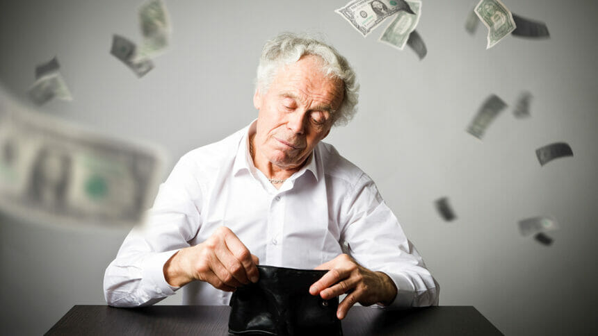 Old man in white and empty wallet. Accounting and taxes concept. Falling dollars.