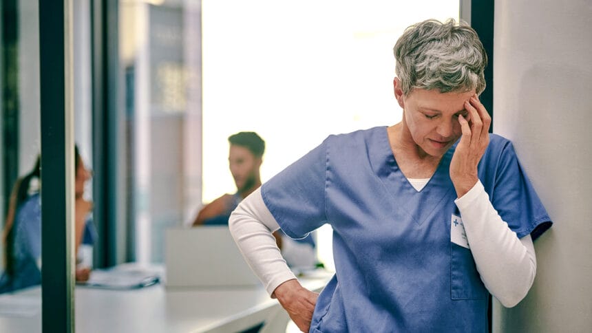 Shot of a mature female nurse suffering from a serious headache while working inside a hospital