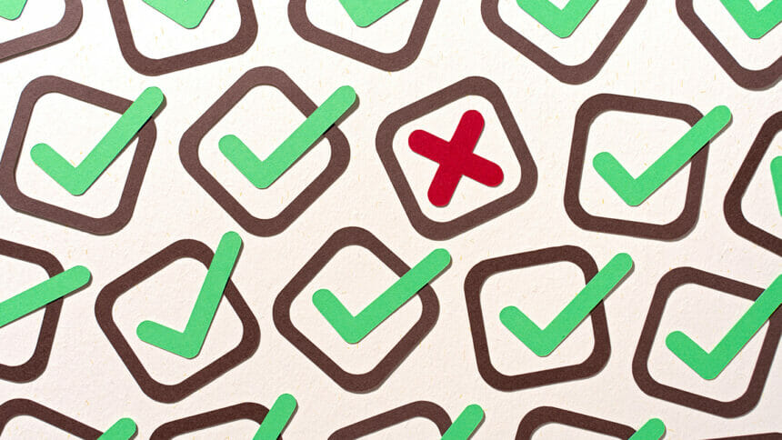 A Single Cross Mark Stands Out From Many Check Marks Paper Craft on Beige Background Directly Above View.
