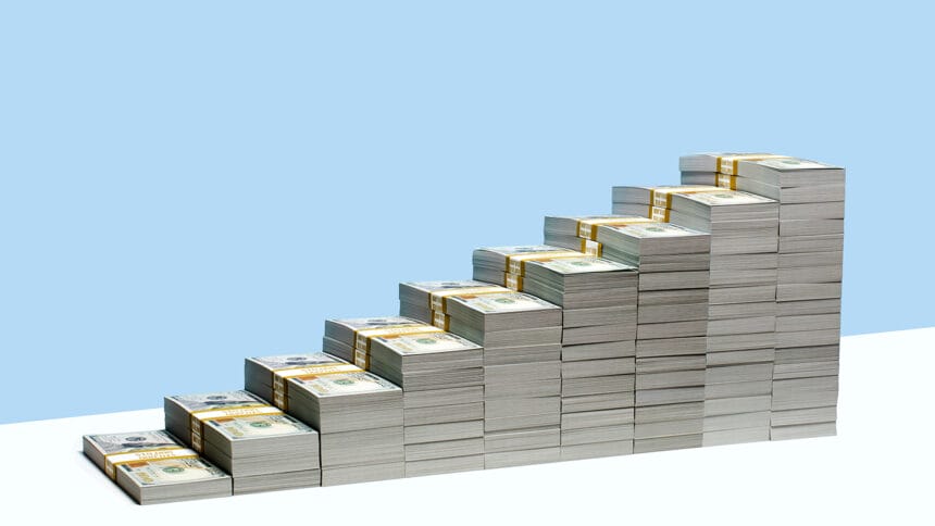 9 stacks of US $100 bill bundles in ascending size order on white shelf, blue background, money