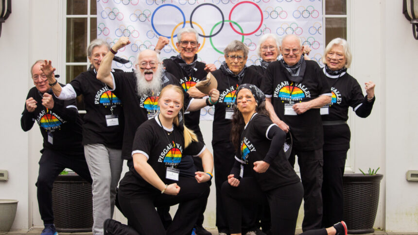10 people posing in front of an Olympic banner