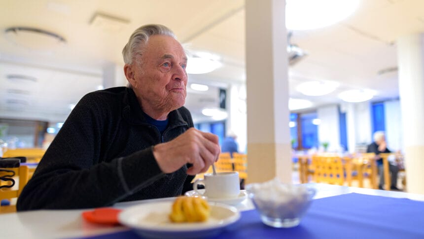 Portrait of senior man relaxing while eating at the cafeteria of nursing home in Turku, Finland