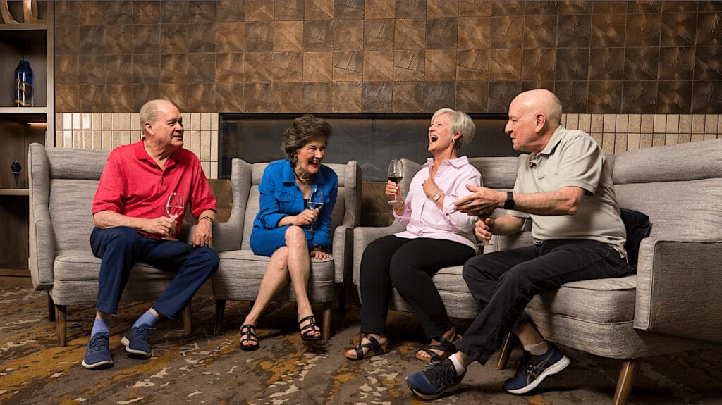 Four older adults socializing and drinking wine