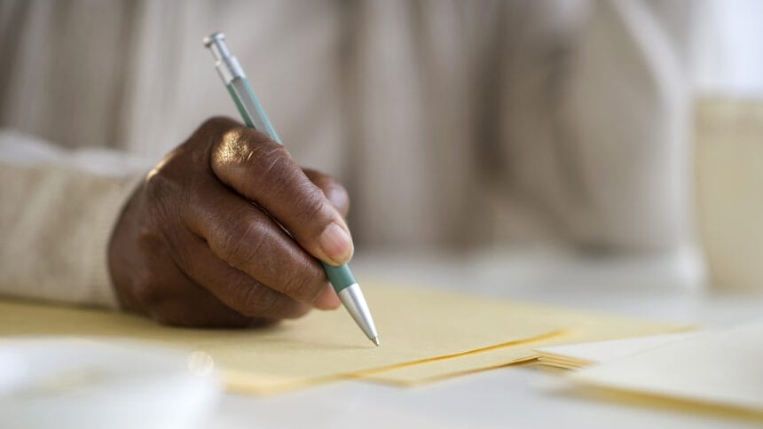 hand with pen writing on paper