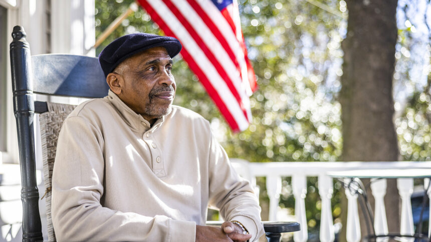 Senior Black man in rocking chair on front porch