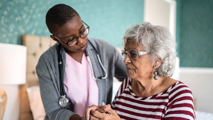 Home caregiver helping a senior woman standing in the bedroom