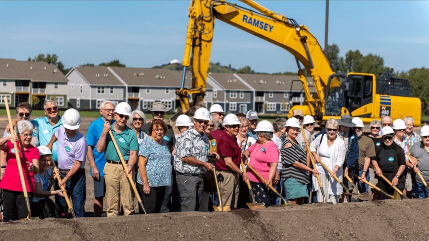 a bunch of people holding shovels in front of construction equipment and in back of a pile of dirt