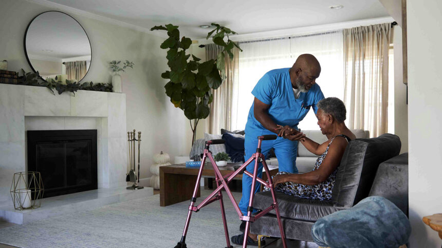 Worker helping a woman to her walker.