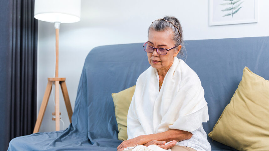 Depressed lonely senior woman sitting on the sofa at home