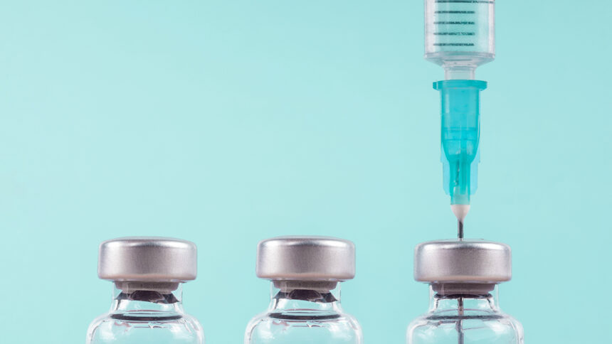 Row of medical vials and syringe. Glass bottles with a transparent potion on a light background