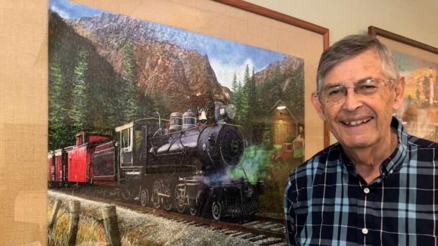 Dan Leclerc in front of a framed puzzle