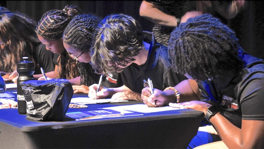 students at a table signing documents