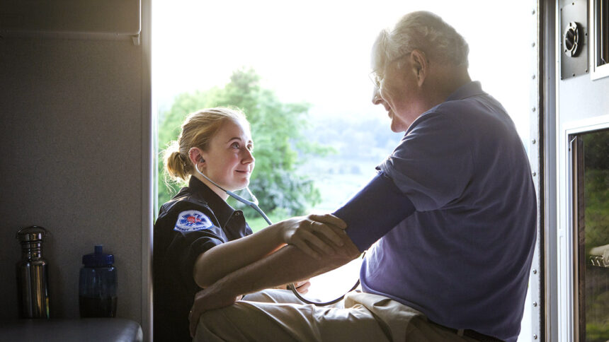 Paramedic checking mans blood pressure in ambulance